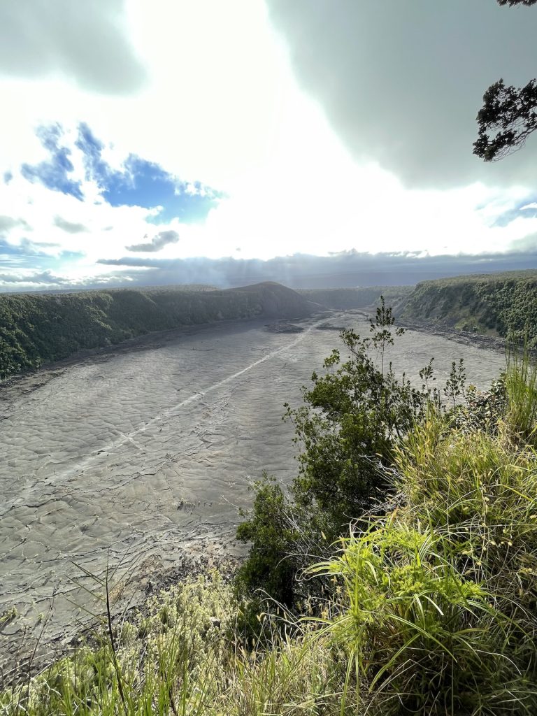 View of the Kīlauea Caldera at Hawai‘i Volcanoes National Park under a bright, cloudy sky.