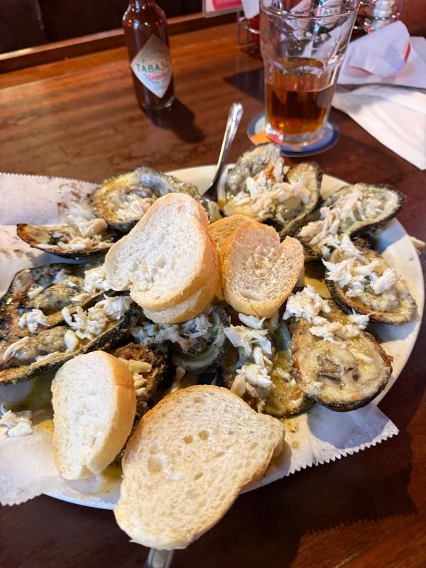 A platter of baked oysters topped with crab meat and toasted bread, a classic dish found in a New Orleans food guide.