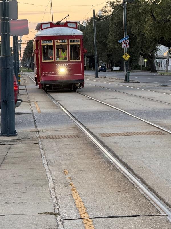A red Canal streetcar approaches on tracks along a paved street in this New Orleans travel guide.